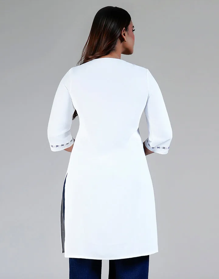 Back view of a white tunic with 3/4 sleeves and embroidered cuffs. Plain V-neck, side slits. Model wearing dark pants. Gray background.